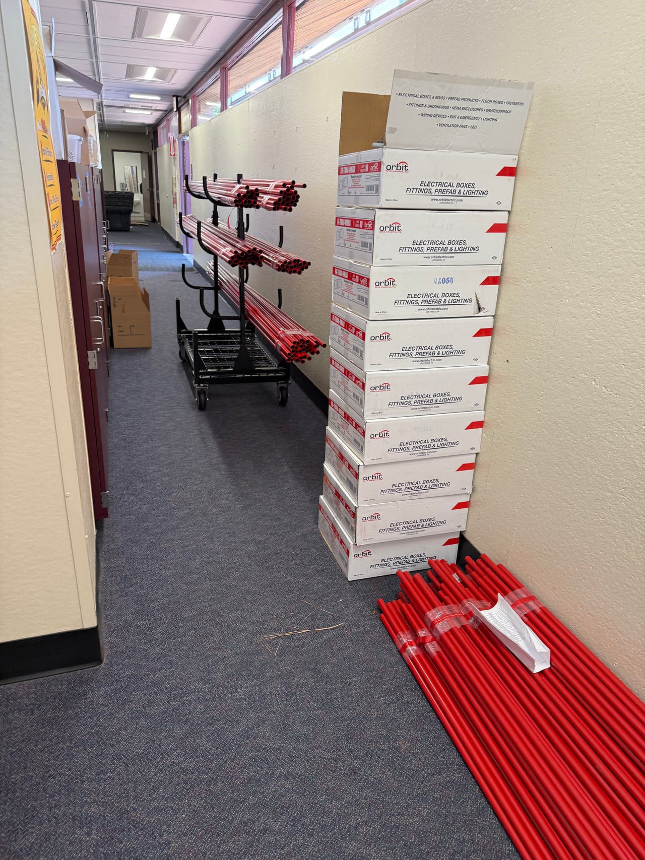 Red conduit and installation materials staged in a Fremont Elementary hallway
