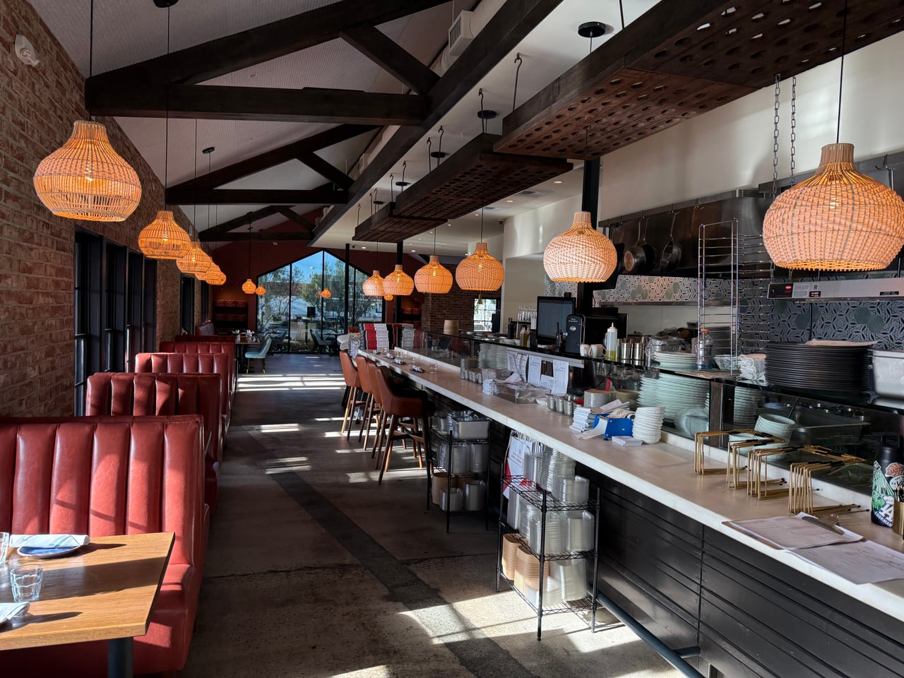 Woven pendant lights above the open kitchen counter and booth seating at OSPI