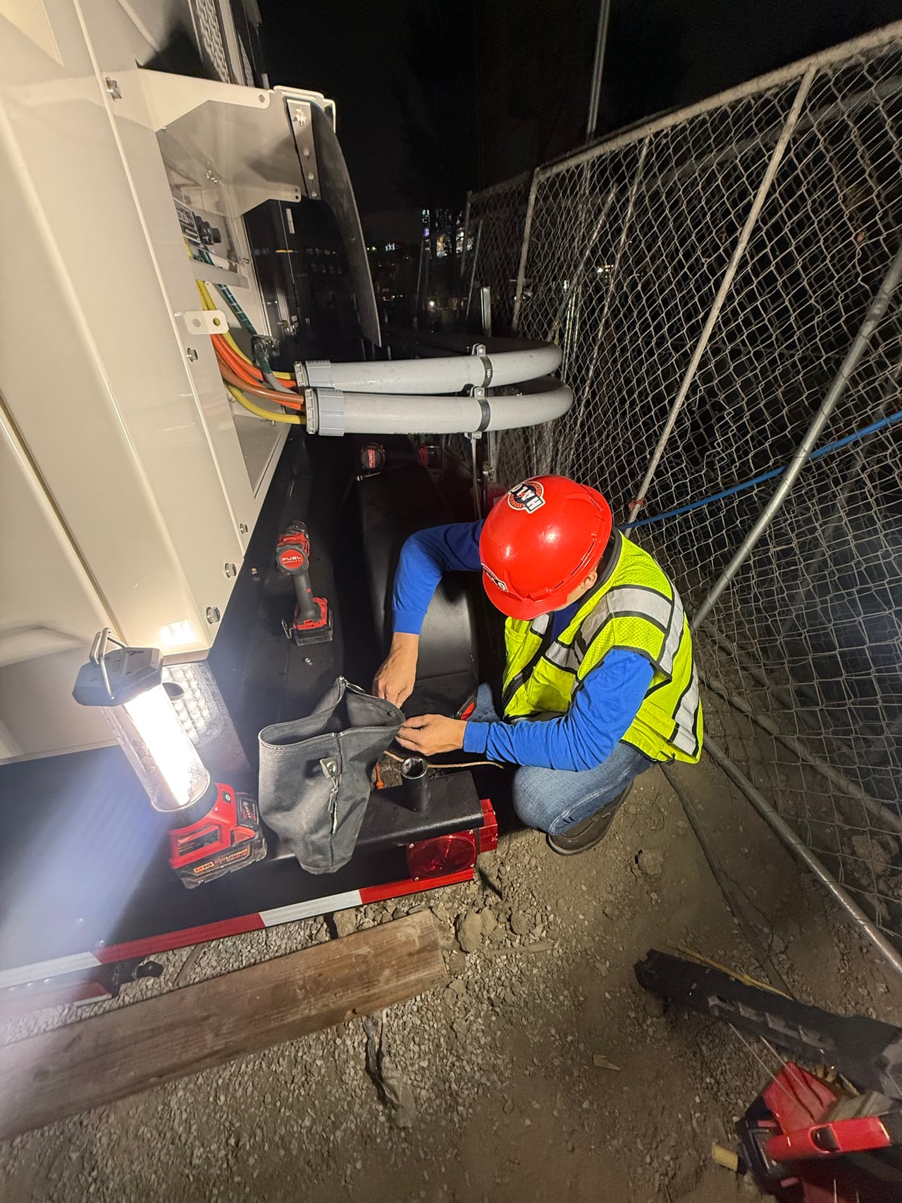 Halo technician beside electrical equipment at night, illuminated by a portable work light