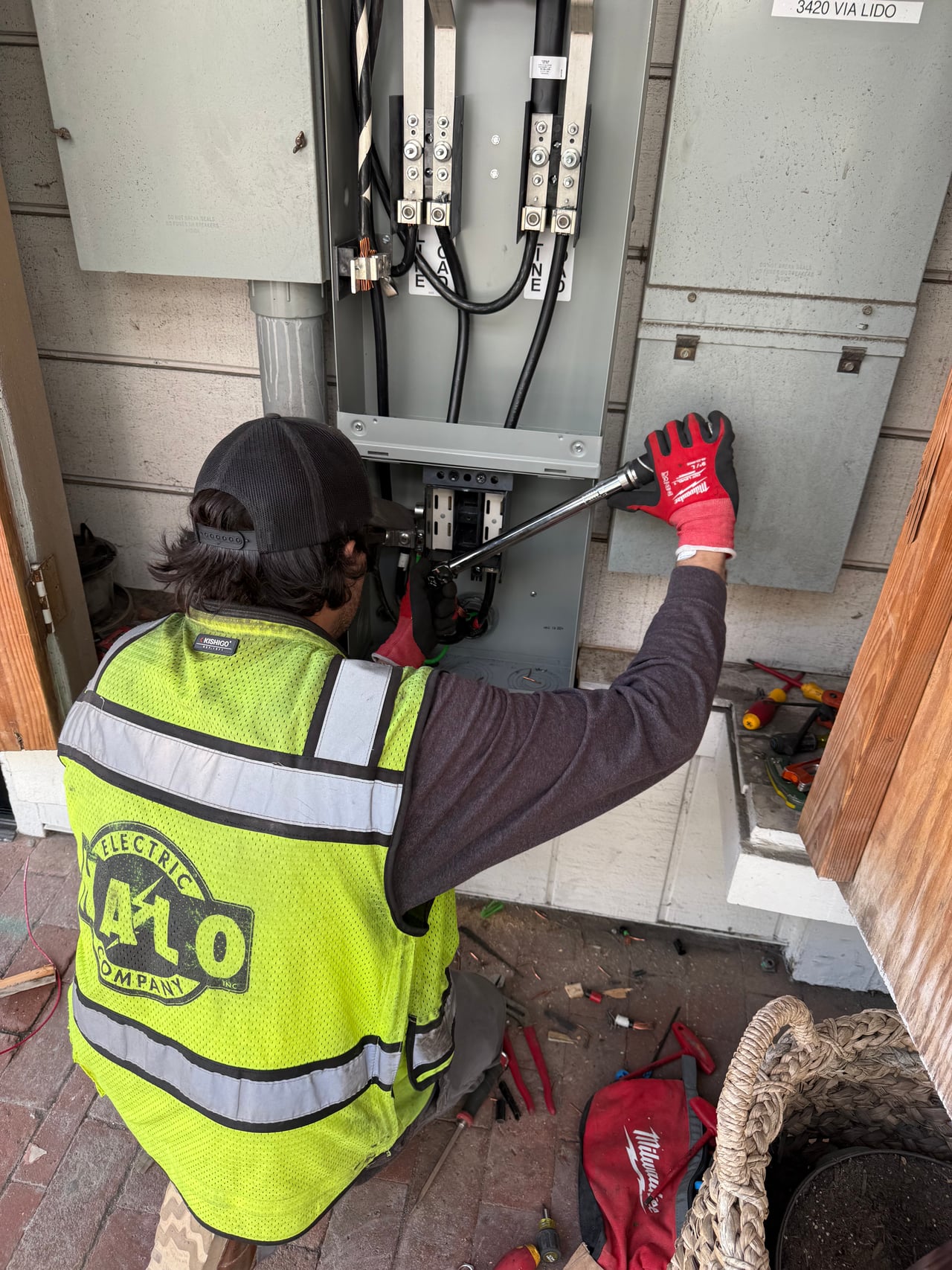 Halo technician in a company safety vest working on electrical service equipment