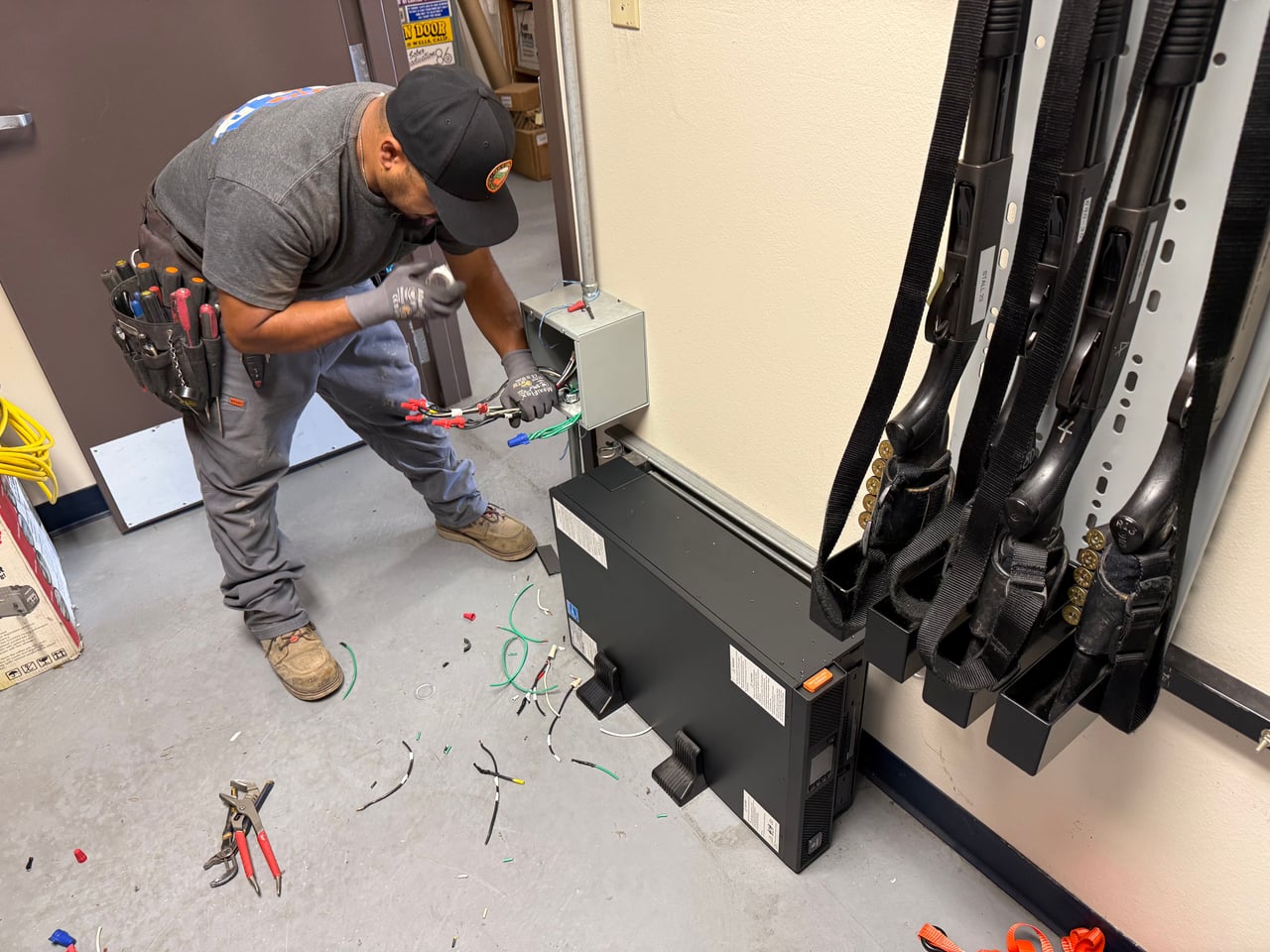 Halo technician working on electrical connections beside wall-mounted equipment