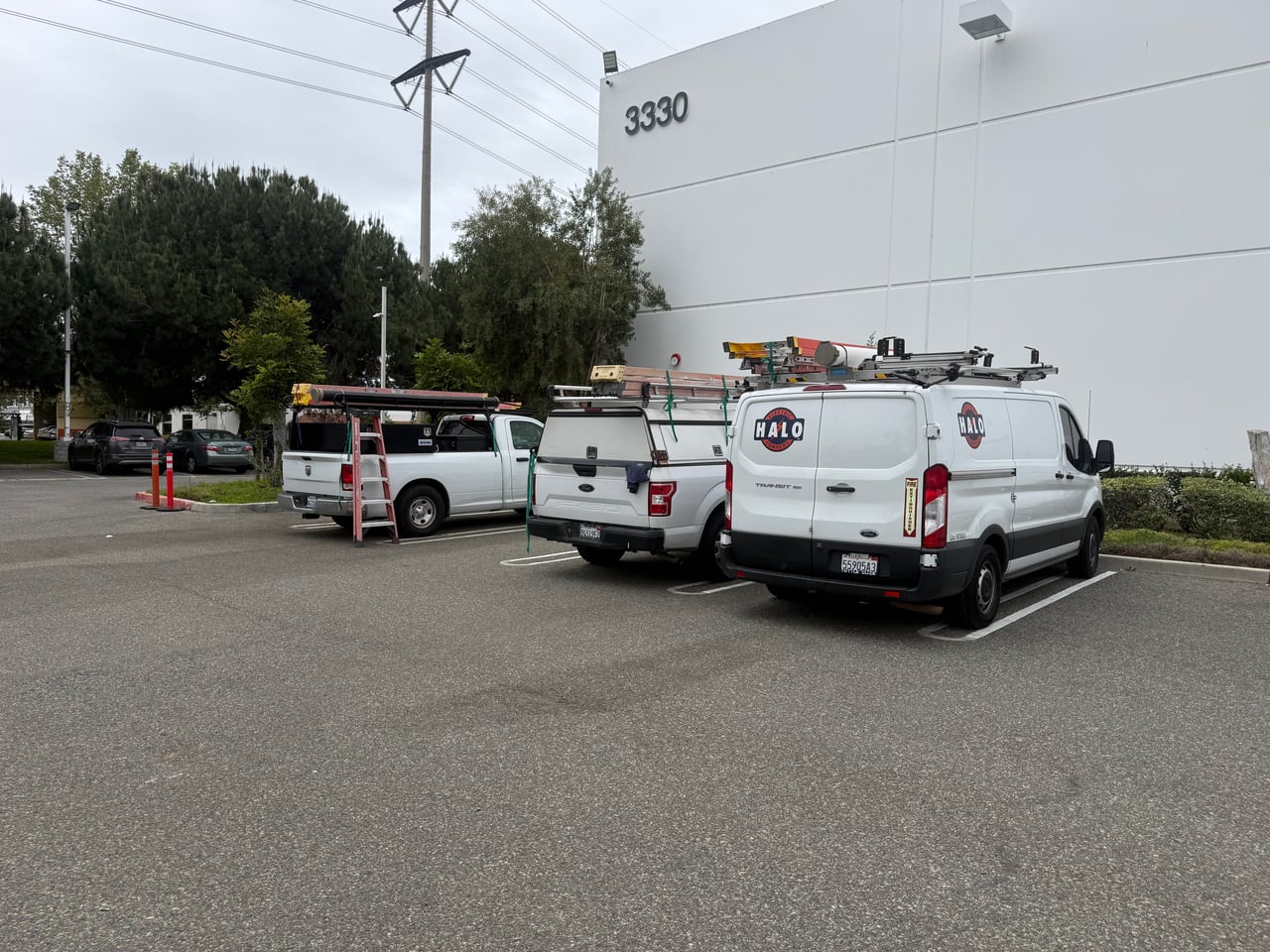 Halo Electric van and work trucks parked at a commercial building