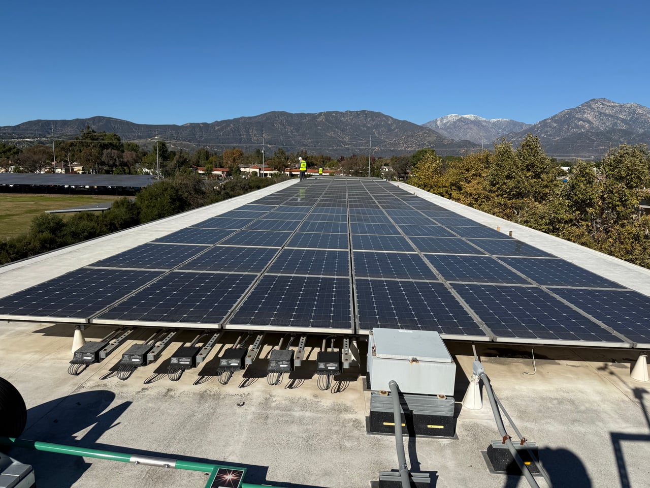 Rows of rooftop solar panels with crew members at the far end of the array